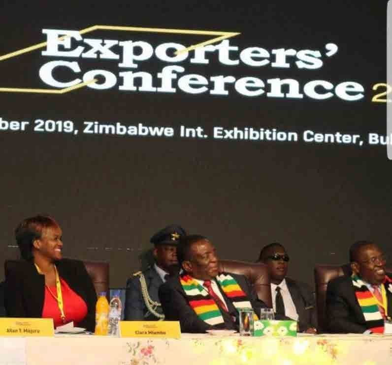 Exporters Conference stage with Clara seated at a panel table.